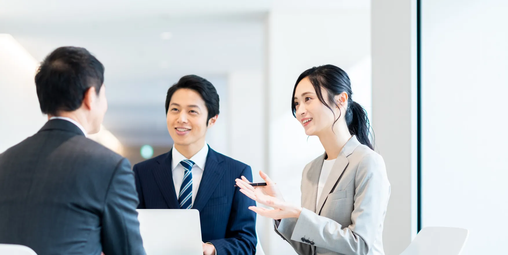 オフィスで打ち合わせをするスーツ姿の3人